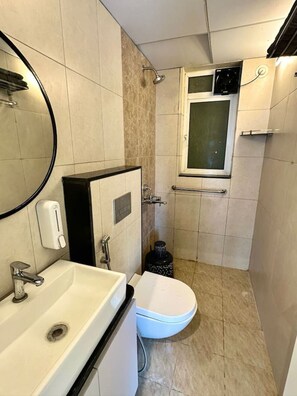 Een kleine badkamer met een wastafel, toilet en douche.