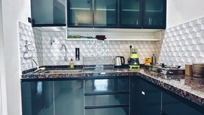 Una cocina moderna con armarios oscuros, encimera de granito y salpicadero de azulejos blancos.