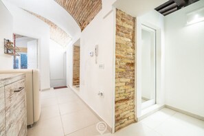 Un interior moderno con zona de cocina, un armario de madera y una pared decorada con ladrillo.