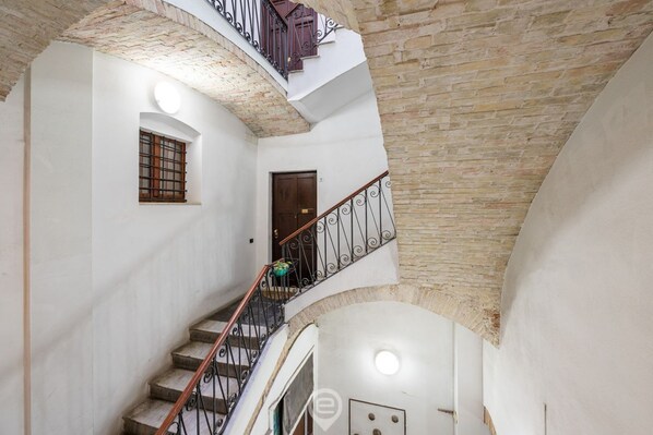 Un interior de varios niveles con una escalera, una puerta y una ventana.