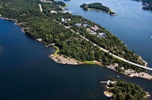 An aerial view of a coastal area with dense forest, a bridge, and several buildings. - Dream Cottage in the Stockholm Archipelago (Djurhamn)