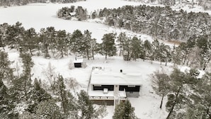 A cabin surrounded by snow-covered trees and a frozen lake. - Dream Cottage in the Stockholm Archipelago (Djurhamn)