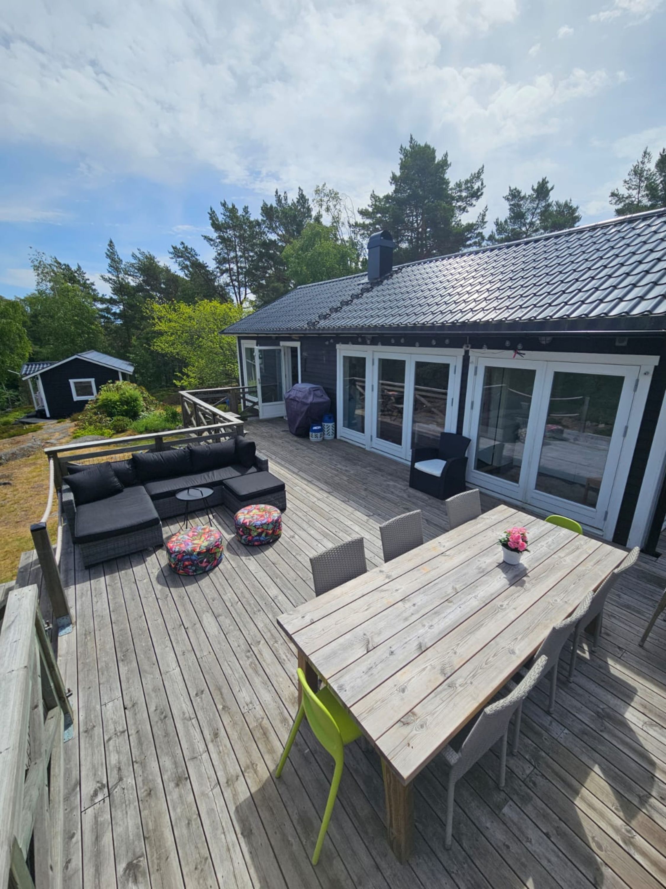 A wooden deck with outdoor furniture, including a sofa, ottoman, and table with chairs.