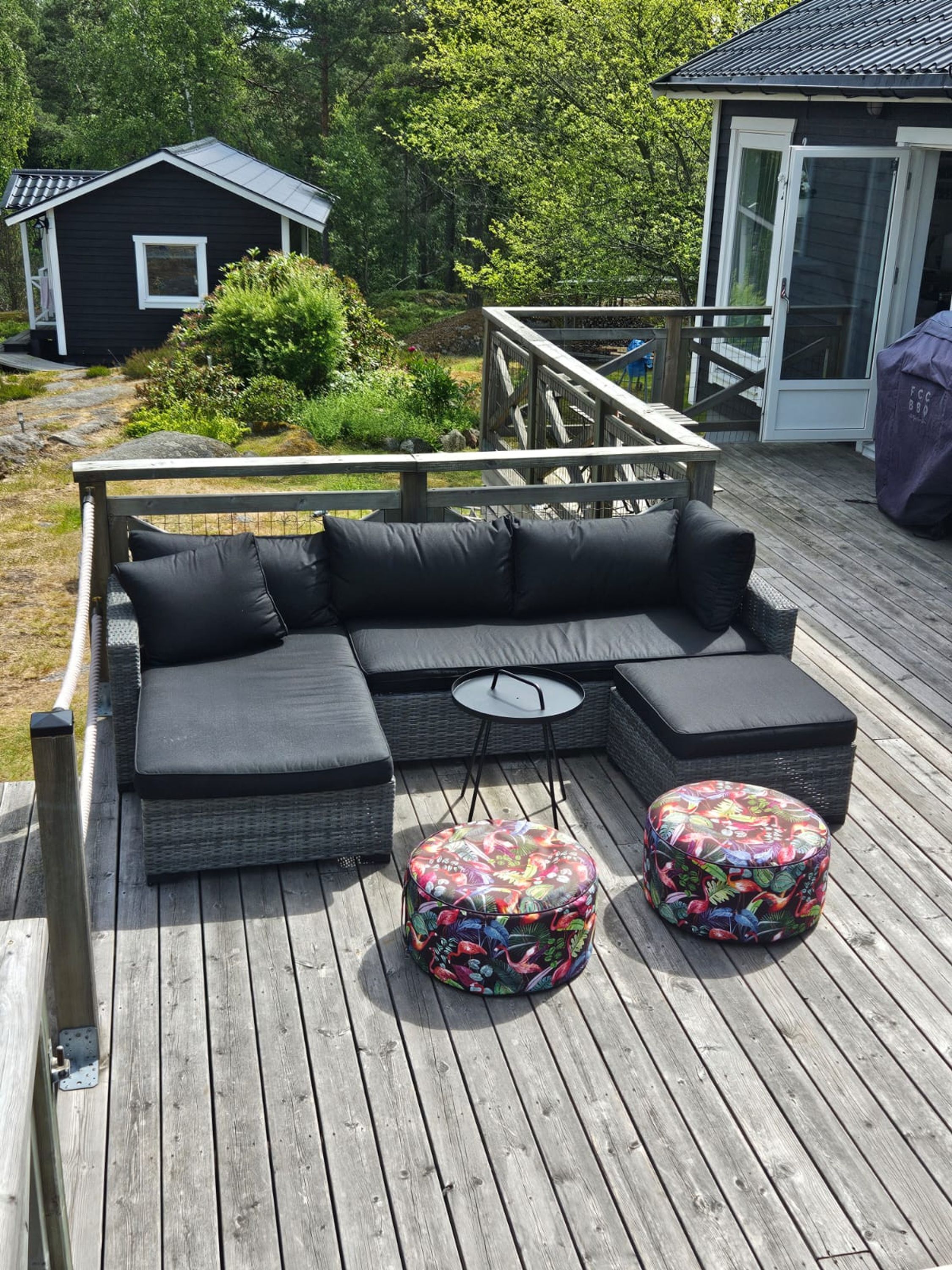 Eine Terrasse mit einer Eckcouch, zwei runden Hocker und einem kleinen Tisch.