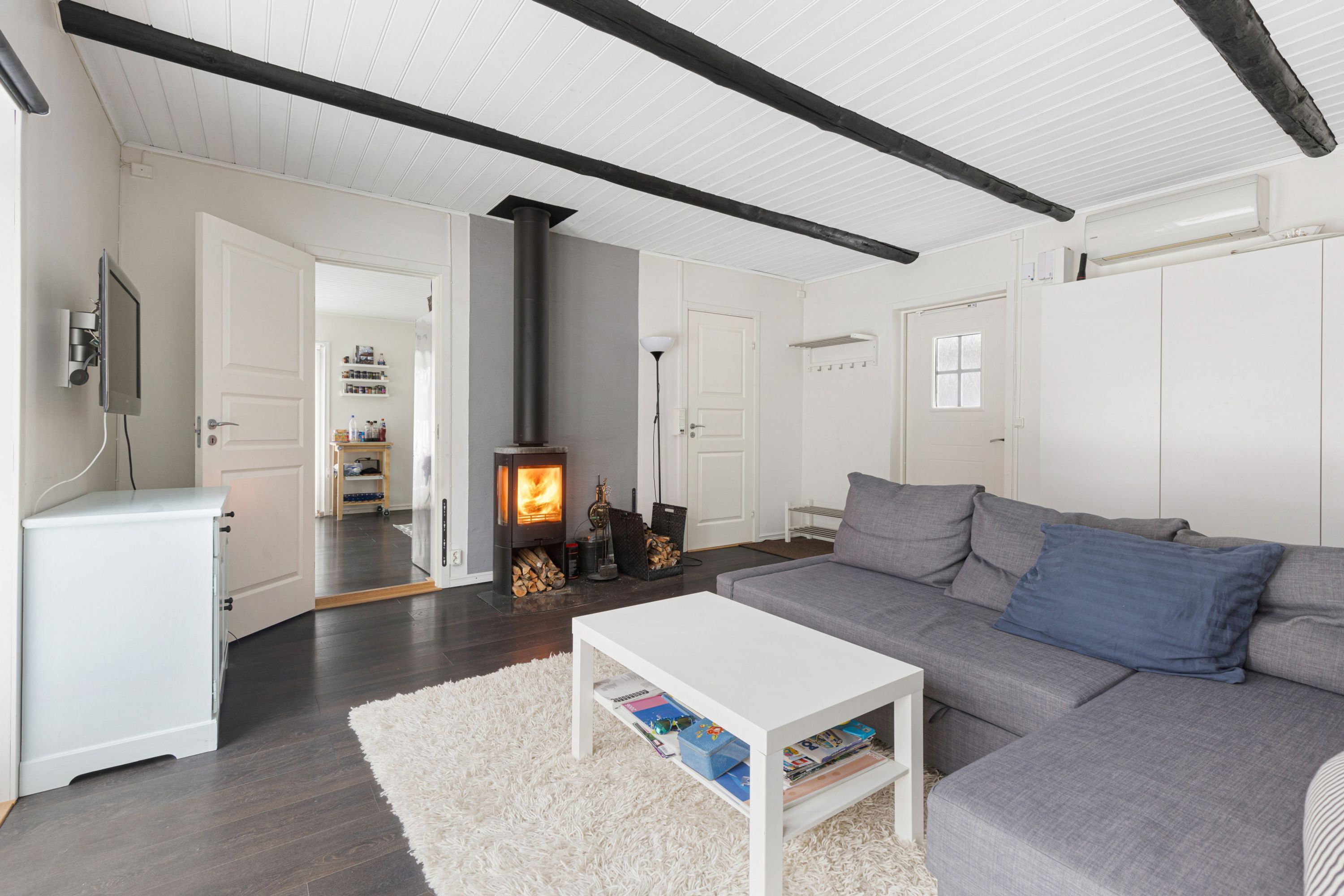 A modern living room with a grey sofa, white coffee table, and a white fireplace.