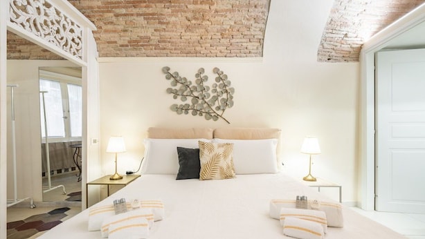A hotel room with a large bed, two bedside tables with lamps, a decorative wall piece, and a view of the outside.