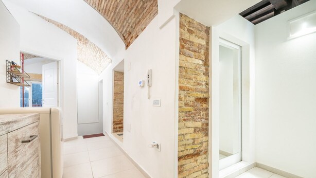 Un intérieur moderne comprenant un espace cuisine, un meuble en bois et un mur d’accent en briques.