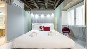 Une chambre à coucher avec un grand lit, un fauteuil rouge et un appareil de climatisation.