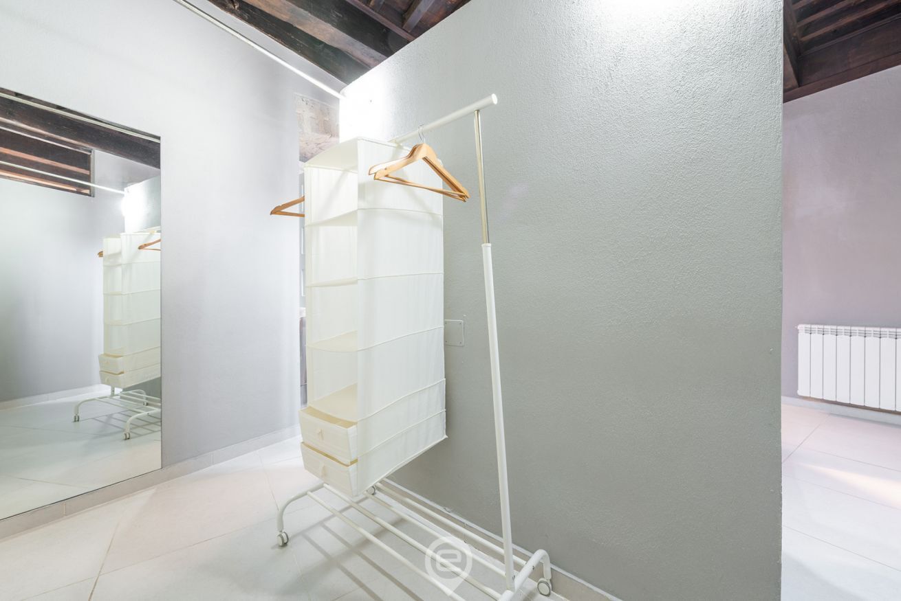 A room with a white wardrobe, a mirror, and a radiator.