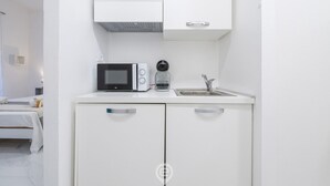 A compact kitchenette with a microwave, coffee maker, and sink. - Guest Room Historic Centre (Iglesias)