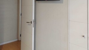 Ett rum med en skjutdörr, en väggmonterad platt-TV och ett golv täckt med matta.