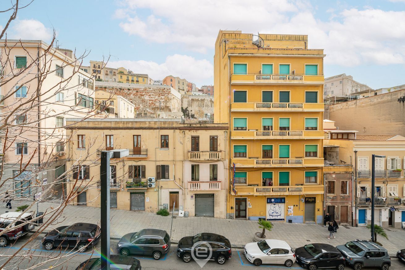 Un edificio a più piani con balconi, auto parcheggiate e cielo sereno.