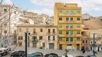 Un edificio a più piani con balconi, auto parcheggiate e cielo sereno.
