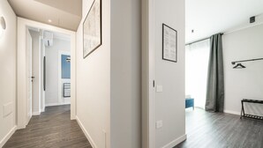 A modern hallway with a wooden floor, white walls, and framed artwork. - Saint Margaret Apartments - Olivia (Cagliari)