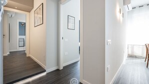 A modern interior with a hallway leading to a room with a wooden floor and a white wall. - Saint Margaret Apartments - Olivia (Cagliari)