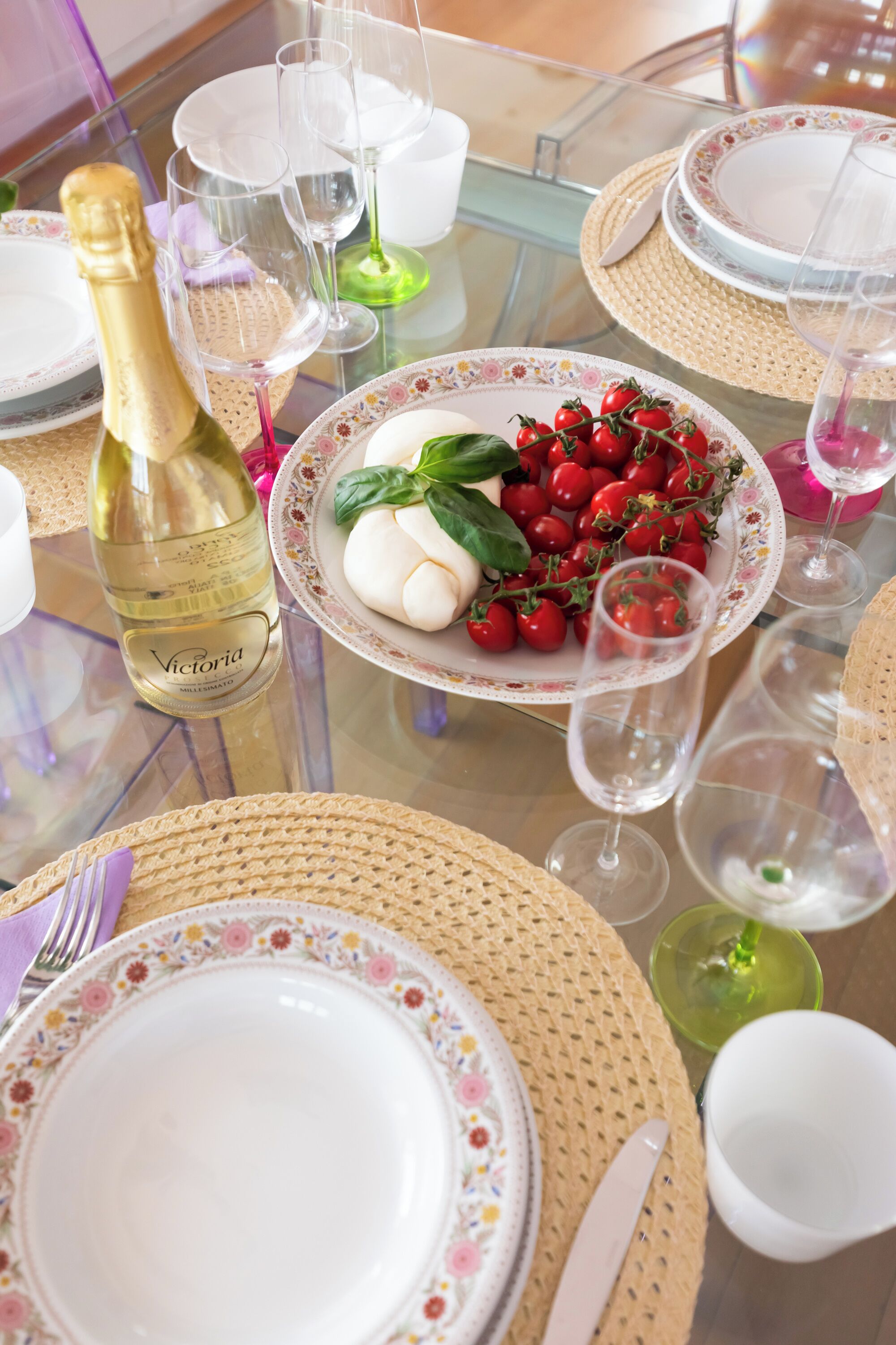 A table set for a meal with plates, glasses, and a bottle of wine.