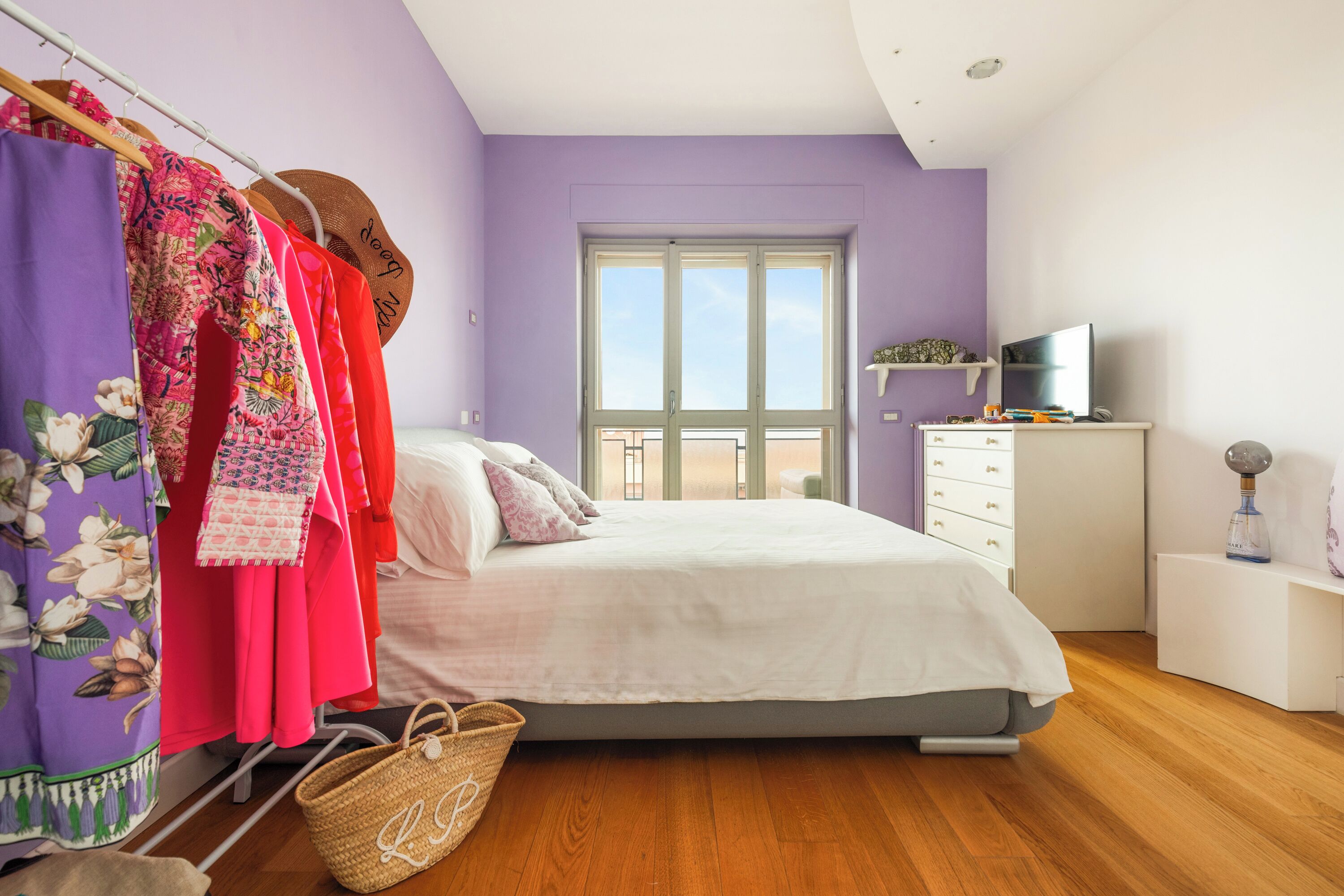 Une chambre à coucher avec un lit, une armoire, une télévision et une fenêtre.