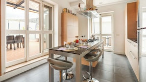 Eine moderne Küche mit Kochinsel, Barhocker und Blick auf die Terrasse.