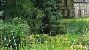 A traditional half-timbered house surrounded by lush greenery and flowering plants.