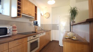 Una cocina compacta con armarios de madera, un microondas, una estufa y un refrigerador.