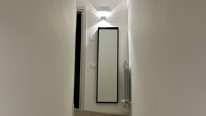 Un escalier avec des marches en bois mène à un palier où l’on aperçoit une porte et un radiateur.