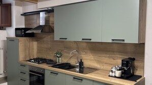 Une cuisine moderne avec un plafond en bois, des appareils électroménagers intégrés et un îlot central doté d’un évier et d’une machine à café.