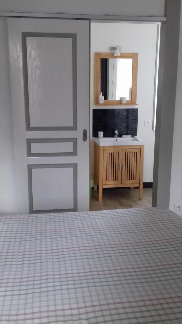 Ein Zimmer mit Schachbrettmuster auf dem Boden, einem Holzschrank mit Spiegel über einem Waschbecken und einer Tür mit geometrischem Dekor.