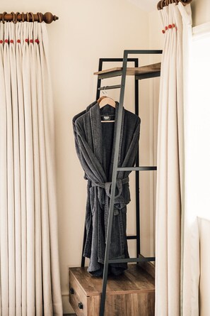A wooden dresser with a robe hanging on a metal rack.