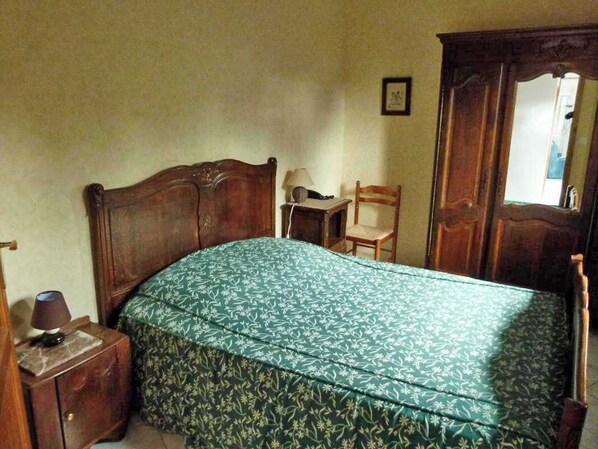 Un dormitorio con cama de madera, mesita de noche, silla y armario.