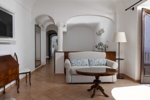 A living room with a sofa, a wooden table, a lamp, and a TV.