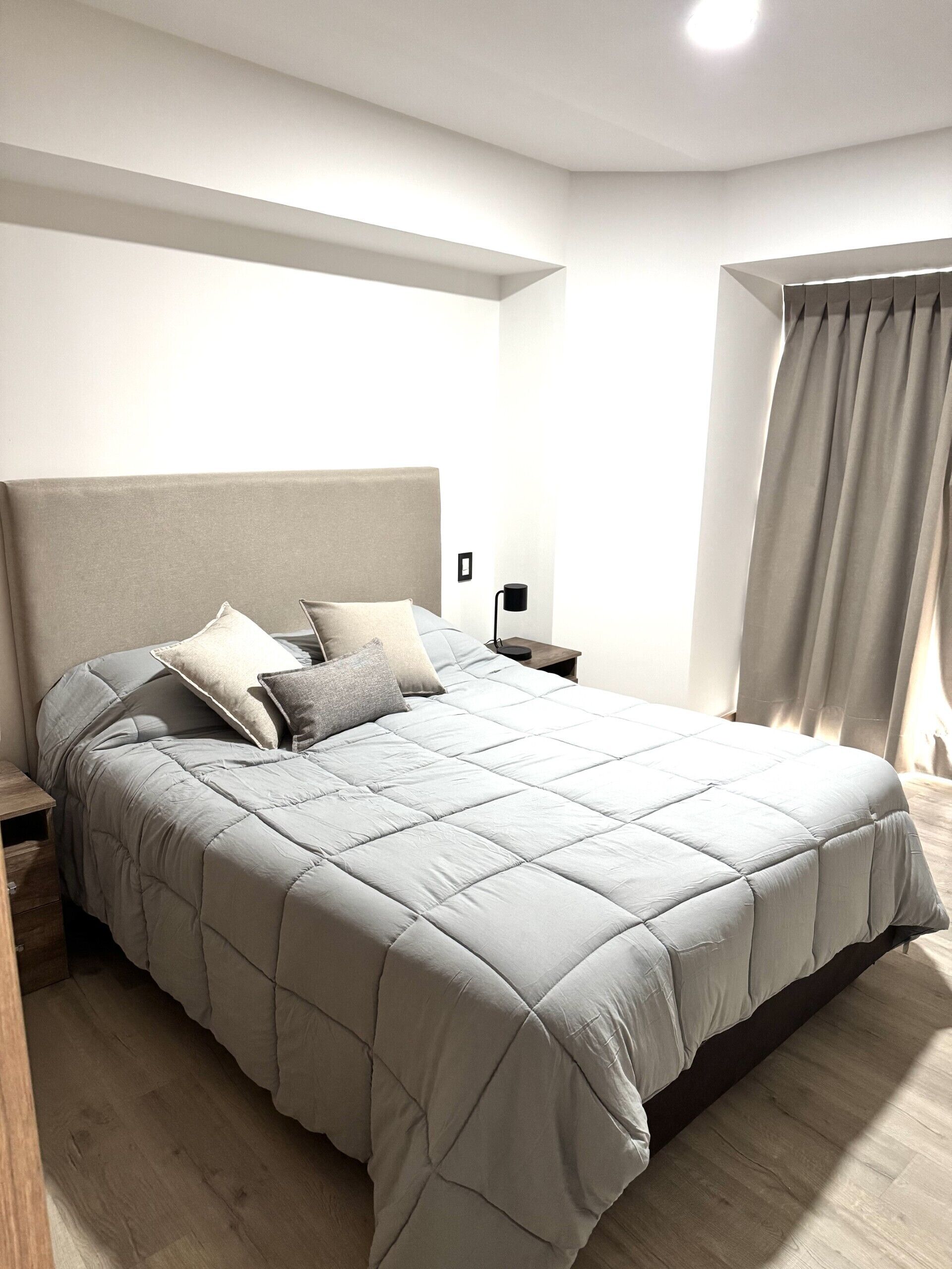 Une chambre à coucher moderne avec un grand lit, une table de chevet et une commode.