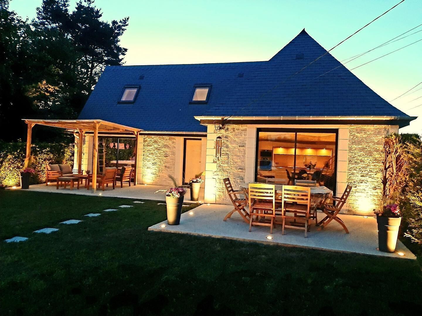 A house with a stone exterior, a covered patio with outdoor furniture, and a visible interior with a dining area.