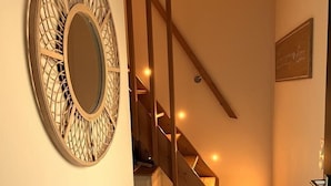 A staircase with wooden steps and a handrail, leading to an upper floor. A decorative mirror is mounted on the wall beside the stairs.