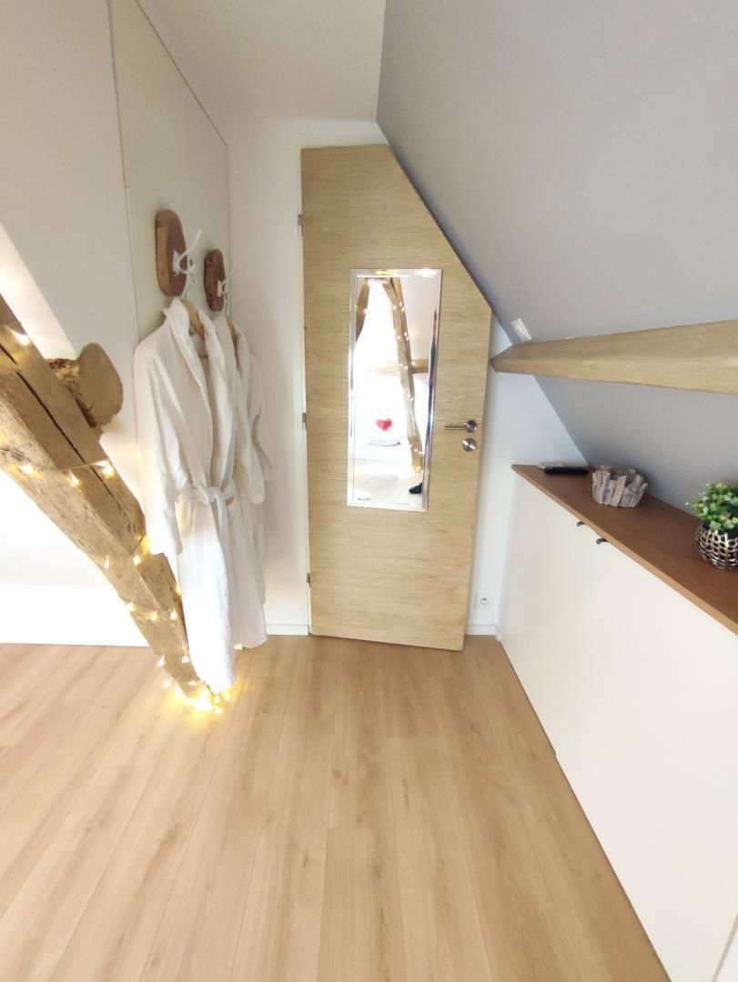 Ein modernes Zimmer mit Holzboden, einer Holztür und einem kleinen Regal mit einer Pflanze.