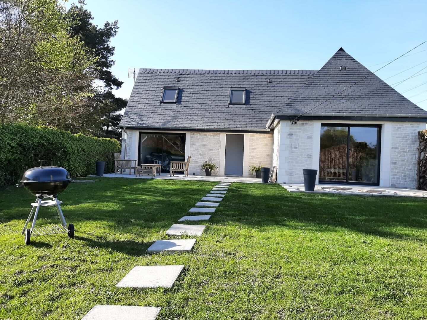 Ein modernes Haus mit Satteldach, Garage und gepflegtem Rasen mit trittfesten Steinen, die zur Haustür führen.