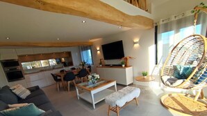 A modern living room with a sofa, a coffee table, and a dining area with chairs and a TV.