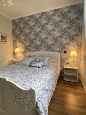 Relax in this serene bedroom with a large bed, floral headboard, and mountainous landscape wall design.