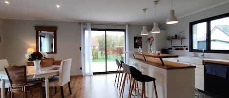 Una cocina moderna con una isla central, taburetes de bar e iluminación colgante.