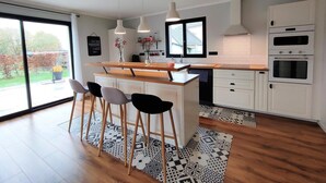 Une cuisine moderne dotée d’un îlot central, de meubles blancs et d’une grande fenêtre.