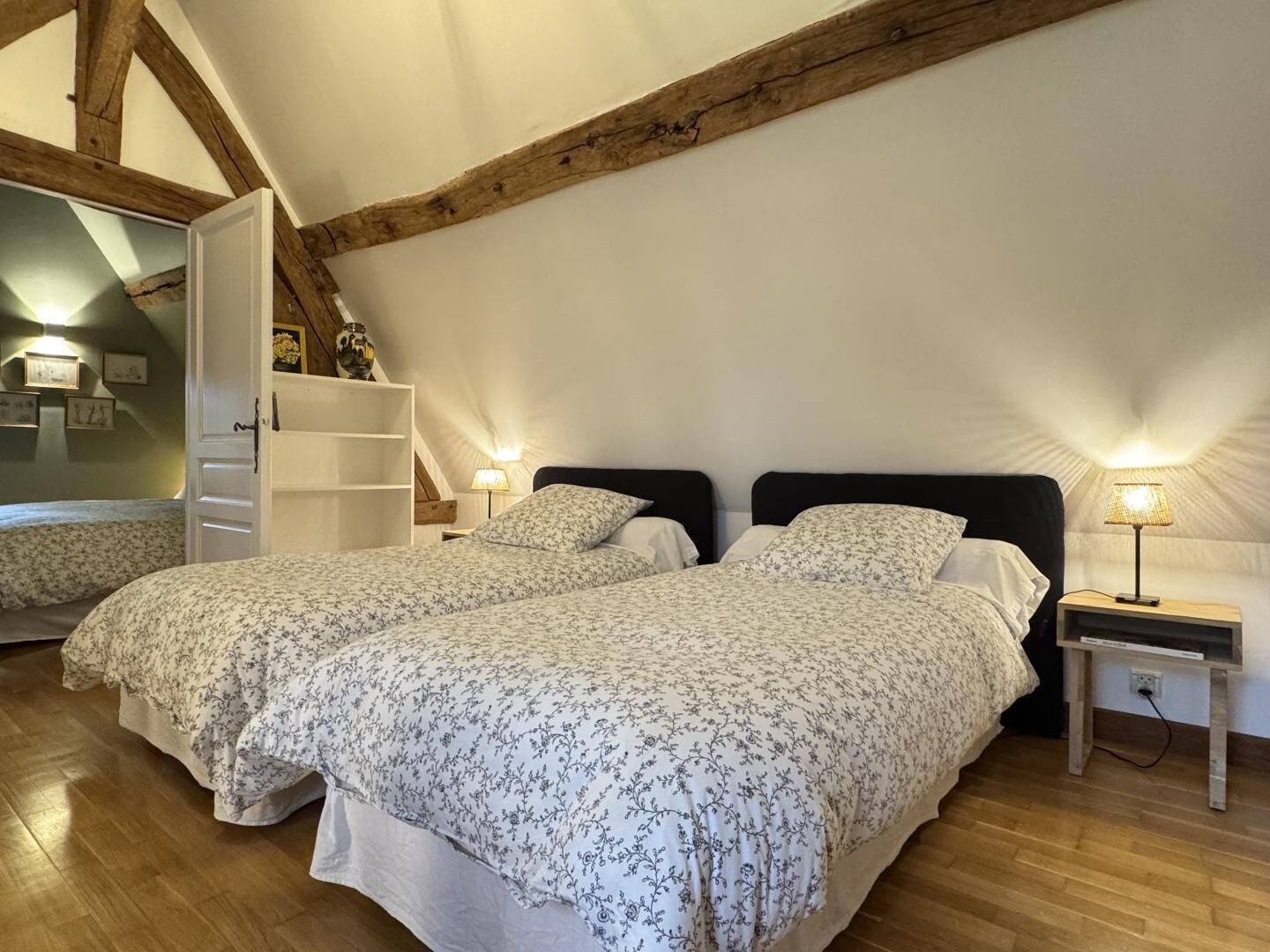 Ein Schlafzimmer mit zwei Betten, Holzbalken, einem weißen Kleiderschrank und einem Nachttisch mit Lampe.