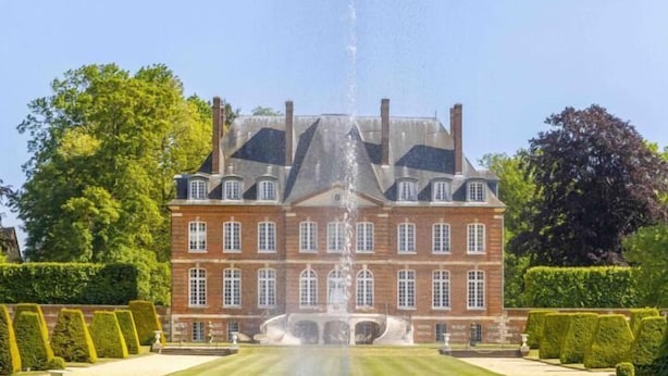 A large building with a fountain in front, surrounded by well-manicured lawns and hedges. - Gîtes de France® - La Maison Rouge (BOIS HEROULT)