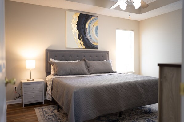 A bedroom with a bed, nightstand, lamp, and abstract art on the wall. - Economical Escape to Edgewood Getaway (Valdosta)