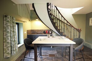 Un espace repas comprenant une table, des chaises et un escalier en colimaçon.