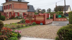 A brick house with a red fence and a gravel driveway. - Gîtes de France® - Auleclairlogis (ETAINHUS)