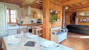 Una cocina con vigas de madera, una mesa de comedor preparada para cuatro personas y un sofá en la sala de estar.