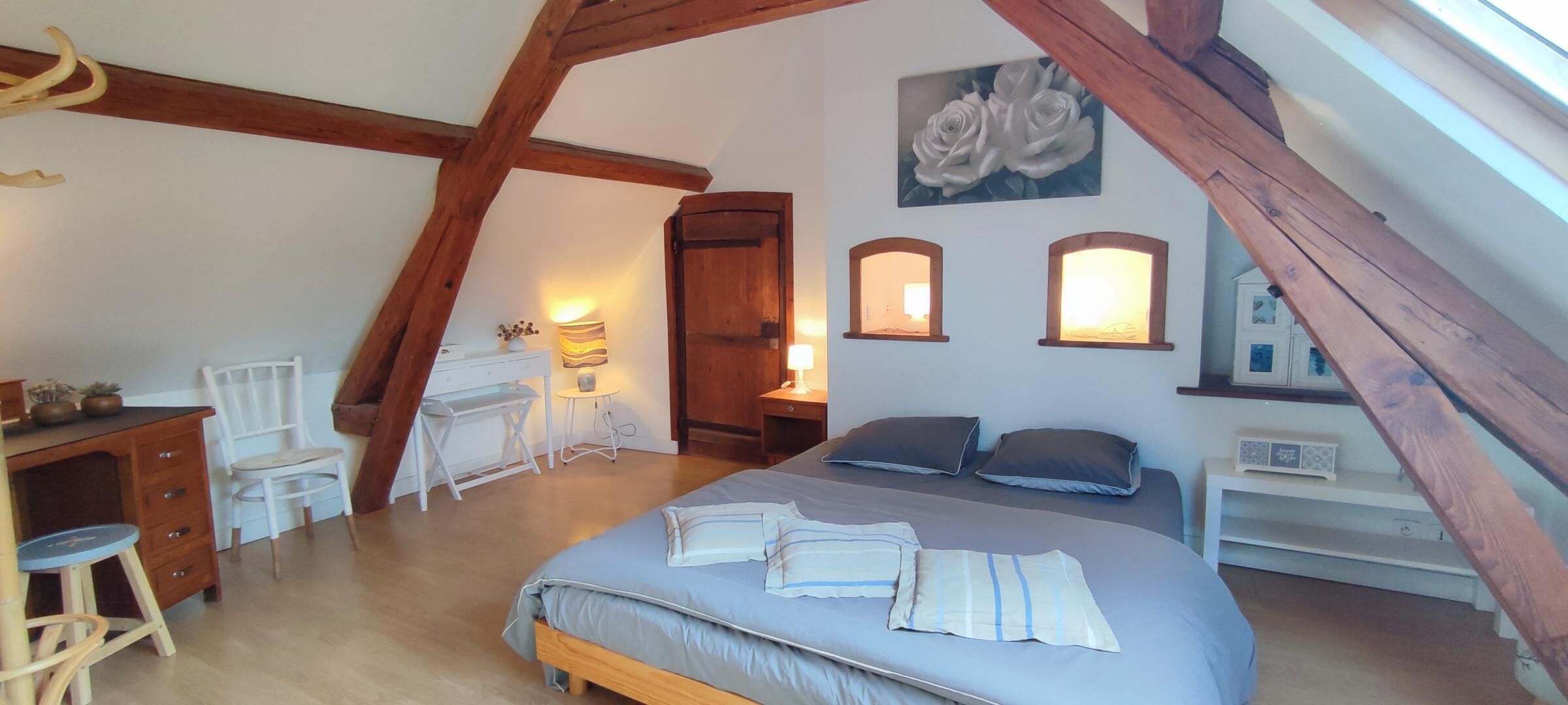 Une chambre à coucher avec un lit, des tables de chevet, un bureau et une chaise.