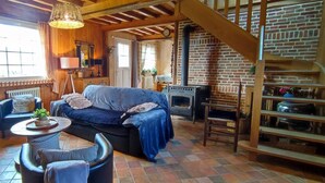 Una habitación acogedora con sofá, sillas, una mesa, chimenea y una escalera.