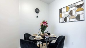 Un comedor con una mesa redonda, sillas negras, un reloj en la pared y un espejo decorativo.