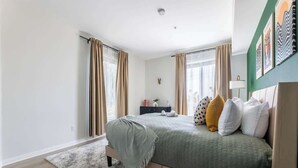 Un dormitorio moderno con cama, cortinas, una mesita de noche y una lámpara de pared.