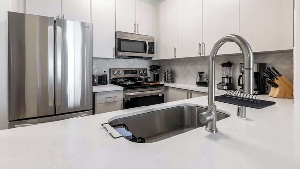 Una cocina moderna con electrodomésticos de acero inoxidable, microondas integrado y un grifo elegante.